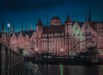 View of illuminated buildings by river at night