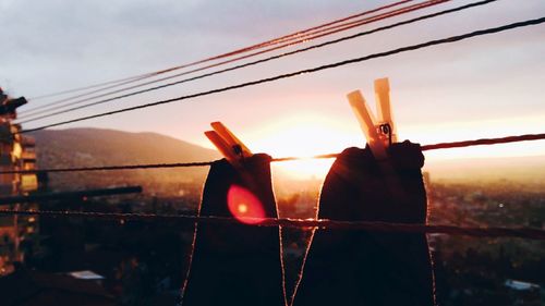 Close-up of clothespins on clothesline against sky during sunset