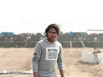 Portrait of young man standing on land against clear sky