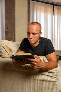 Young man using mobile phone while sitting on sofa at home