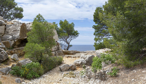 Scenic view of rocks by sea against sky