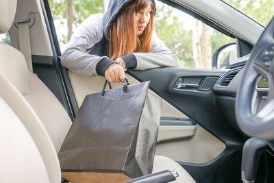 Woman keeping shopping bag in car