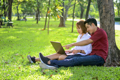 Woman using phone while sitting on grass