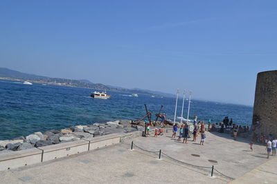 People on beach against clear blue sky