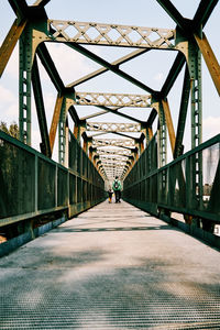 Rear view of man walking on footbridge