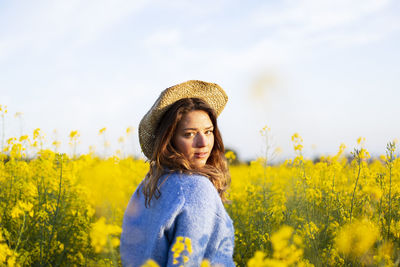 Portrait of beautiful young woman standing on field