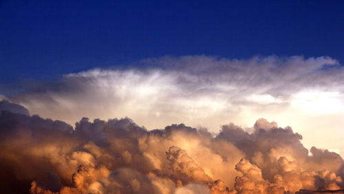 Low angle view of sunlight streaming through clouds