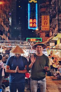 Friends wearing asian style conical hats while standing in market at night