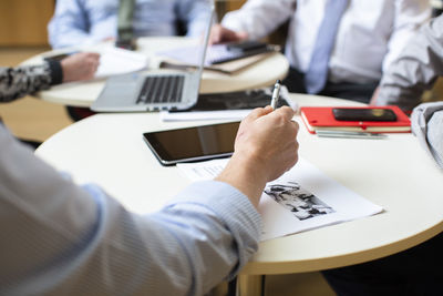 Midsection of man using mobile phone on table