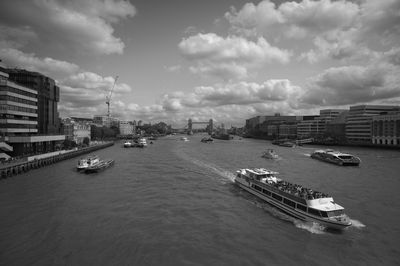 Boats in river amidst buildings in city against sky