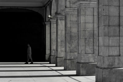 Full length of man walking on corridor by colonnade of historic building