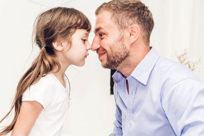 Side view of father and daughter rubbing noses at home