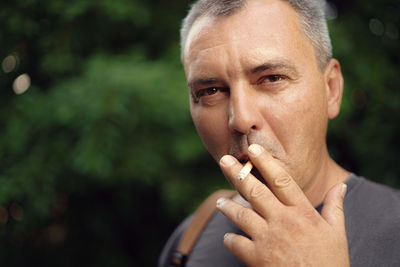 Close-up portrait of man smoking cigarette outdoors