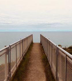 View of wooden bridge over sea against sky