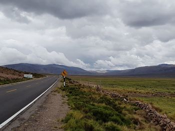 Scenic view of road by mountain against sky