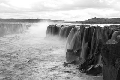 Scenic view of waterfall against sky