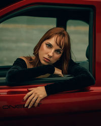 Portrait of a beautiful young woman sitting in car and looking at the camera with a penetrating gaze