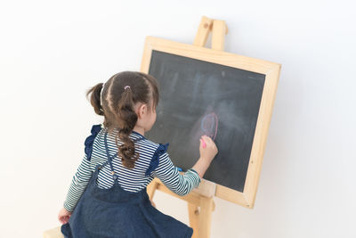 Rear view of woman standing against the wall