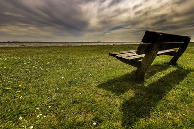 Bench on field against sky