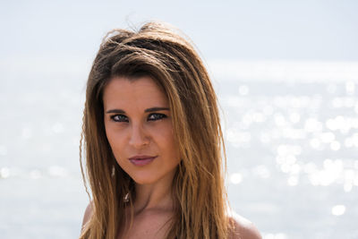 Portrait of beautiful young woman against sea