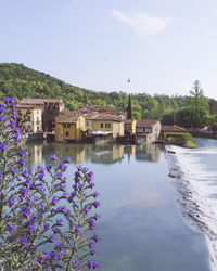 Scenic view of river by buildings against sky