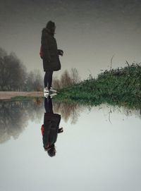 Man standing by lake against sky