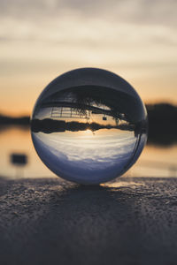Close-up of crystal ball on glass against sunset