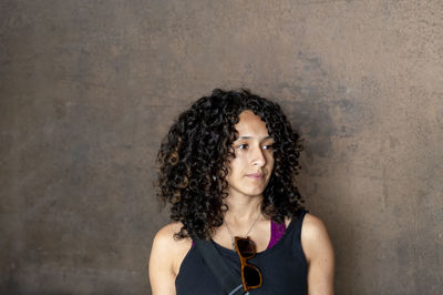 Portrait of young woman standing against wall