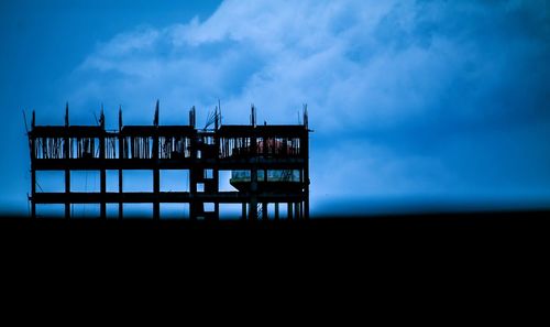 Silhouette pier over sea against sky at dusk