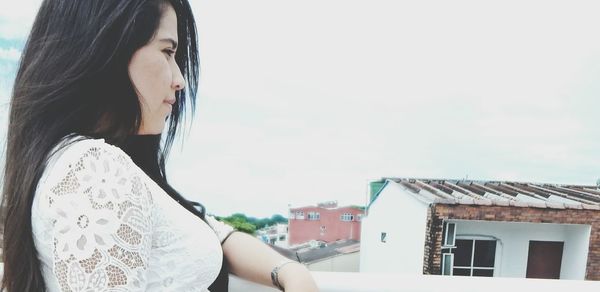 Side view of thoughtful woman standing against sky