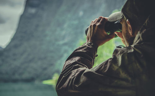 Rear view of hunter looking through binoculars