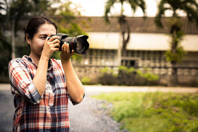 Woman photographing while standing on road