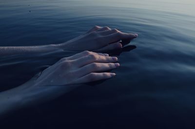 Cropped hand of woman in sea