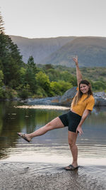 Full length of woman with arms raised in lake