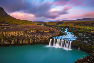 Scenic view of waterfall against sky during sunset