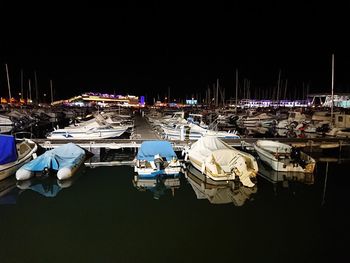 Boats moored at harbor against clear sky at night