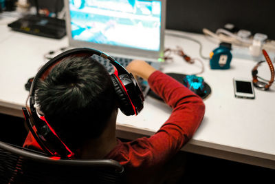 Rear view of boy wearing headphones playing video games