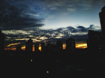 Silhouette buildings against sky at sunset