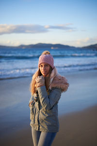 Portrait of young woman standing on beach against sea