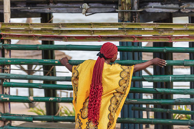 Rear view of person wearing hat against railing