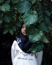 Portrait of teenage girl standing by leaves