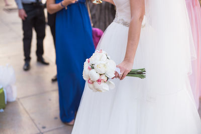 Midsection of bride holding rose bouquet