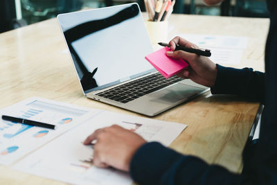 Midsection of man using laptop on table