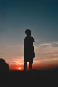 Rear view of man standing against sky during sunset