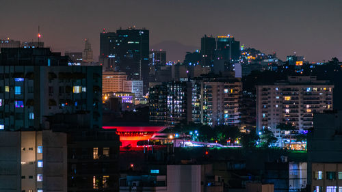 Illuminated buildings in city against sky at night