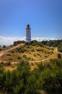 Lighthouse on landscape against sky