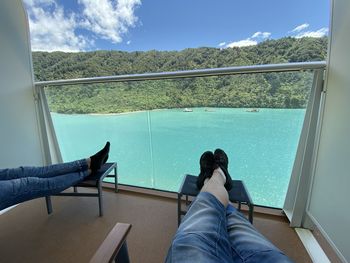 Low section of people relaxing on a ships balcony against turquoise ocean and blue sky
