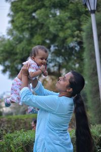 Side view of mother carrying daughter at park