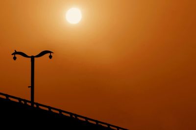 Low angle view of street light against orange sky