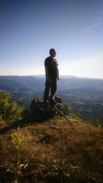 Rear view of man standing on mountain against clear sky